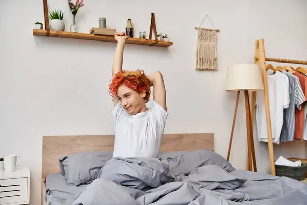 Extravagante jovem queer pessoa em traje casual acordar e esticar em sua cama, tempo de lazer — Fotografia de Stock