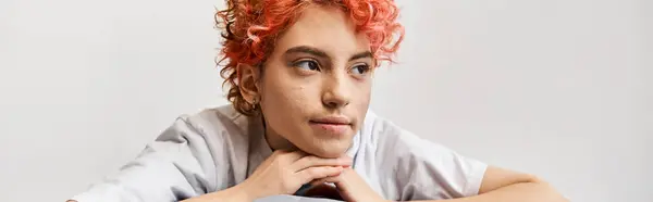 Relaxante vermelho cabelo queer pessoa sentada em sua cama em casa e olhando para longe, tempo de lazer, banner — Fotografia de Stock
