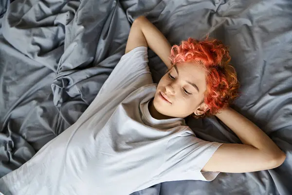 Bella persona stravagante con i capelli rossi vibranti sdraiati nel suo letto e guardando altrove, tempo libero — Foto stock