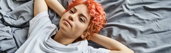 Attraente persona stravagante con i capelli rossi sdraiati nel suo letto e guardando altrove, tempo libero, banner — Foto stock