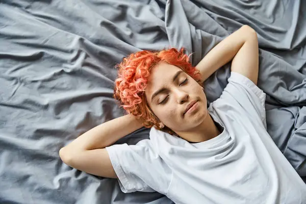 Good looking jolly queer person in cozy homewear relaxing on her bed with closed eyes, leisure time — Stock Photo