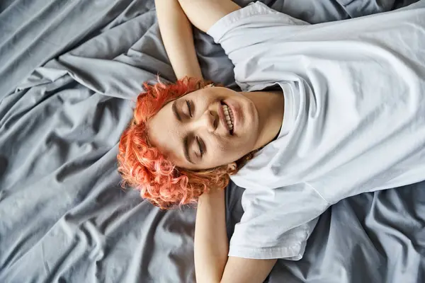 Good looking jolly queer person in cozy homewear relaxing on her bed with closed eyes, leisure time — Stock Photo
