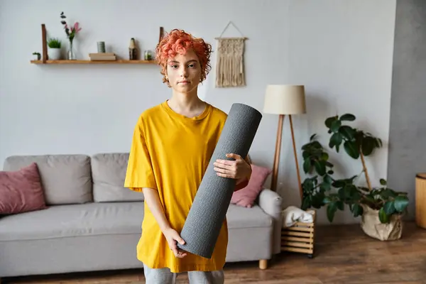 Sporty giovane persona queer con i capelli rossi in abbigliamento vibrante in possesso di tappetino yoga e guardando la fotocamera — Foto stock