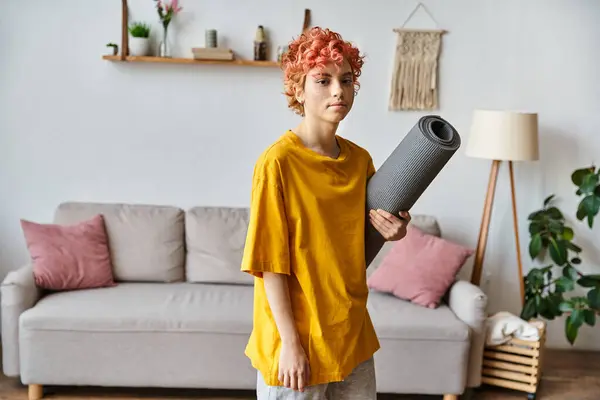 Sporty giovane persona queer con i capelli rossi in abbigliamento vibrante in possesso di tappetino yoga e guardando la fotocamera — Foto stock