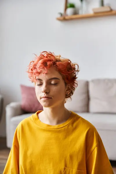 Beautiful extravagant queer person with red hair in vibrant yellow t shirt meditating at home — Stock Photo