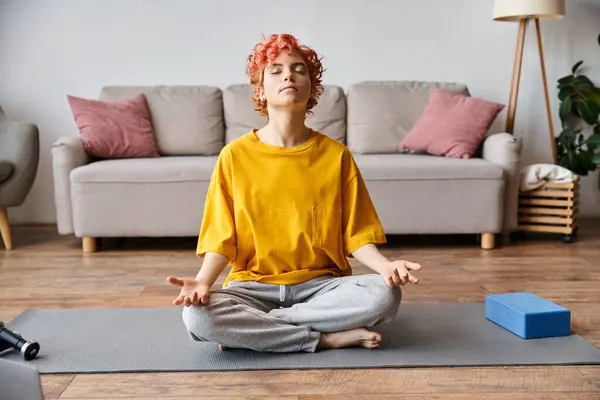 Beautiful extravagant queer person with red hair in vibrant yellow t shirt meditating at home — Stock Photo