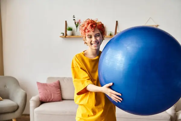 Pessoa extravagante alegre em traje confortável exercitando com bola de fitness e sorrindo para a câmera — Fotografia de Stock