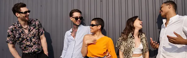 Jolly interracial friends in vivid clothing talking to each other happily and posing by wall, banner — Stock Photo