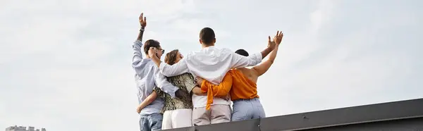 Back view of four young interracial friends in casual urban attires posing on rooftop, banner — Stock Photo