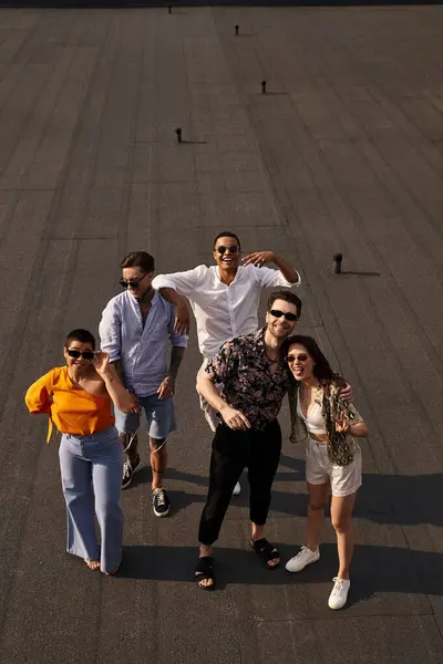 Five multiracial cheerful friends in vibrant attires posing on rooftop and smiling happily at camera — Stock Photo