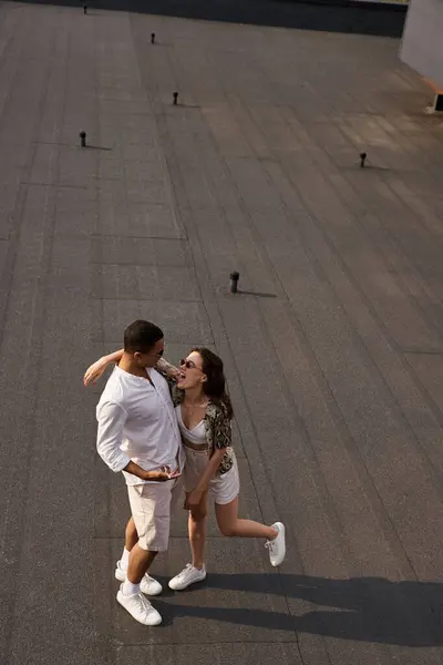 Happy multiracial man and woman in casual attires with sunglasses posing together on rooftop, couple — Stock Photo