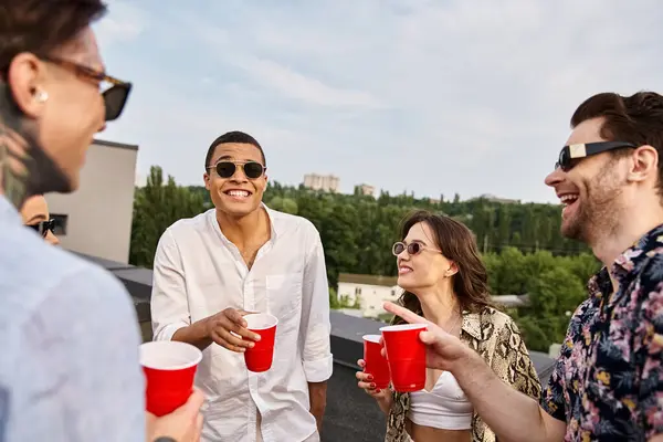 Привабливі веселі різноманітні друзі зі стильними сонцезахисними окулярами проводять час разом на вечірці на даху — стокове фото