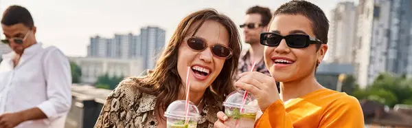 Веселые красивые женщины пьют коктейли на вечеринке на крыше и улыбаются в камеру, баннер — стоковое фото