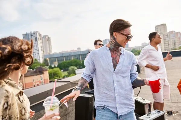 Joyous multiracial friends with sunglasses drinking alcohol at rooftop party and dancing to DJ set — Stock Photo
