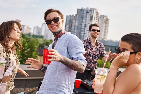 Amigos alegres em trajes casuais com óculos escuros bebendo na festa no telhado e dançando para DJ set — Fotografia de Stock