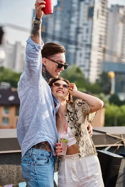 Jóvenes amigos alegres con gafas de sol de moda que se divierten en la fiesta en la azotea con cócteles - foto de stock
