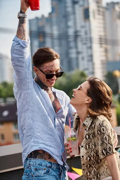 Good looking cheerful man and woman with sunglasses having fun and drinking cocktails at party — Stock Photo