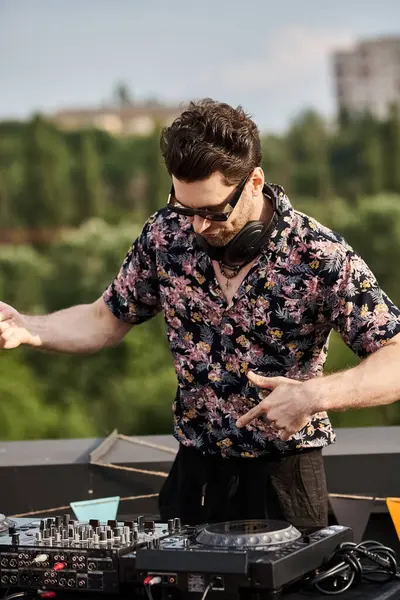 Good looking cheerful man in vibrant attire with sunglasses playing music as DJ at rooftop party — Stock Photo