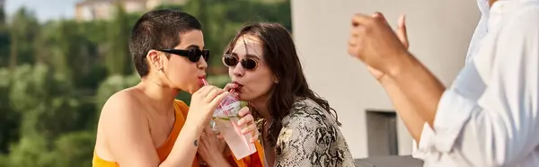 Joyous women drinking from one plastic cup next to african american friend on rooftop party, banner — Stock Photo