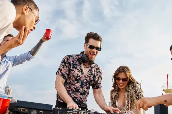 Веселые мультикультурные люди в ярких одеждах с солнцезащитными очками тусуются на крыше DJ set — стоковое фото