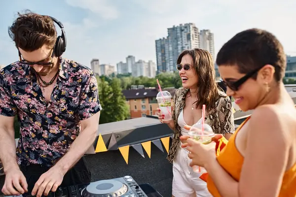 Привлекательные молодые веселые друзья в повседневных нарядах пьют коктейли и веселятся на вечеринке на крыше — стоковое фото