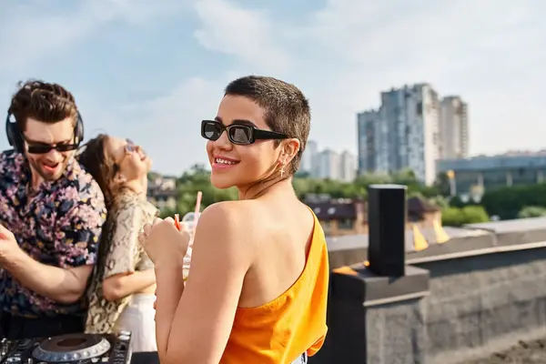 Appealing young joyous friends in casual attires drinking cocktails and having fun at rooftop party — Stock Photo
