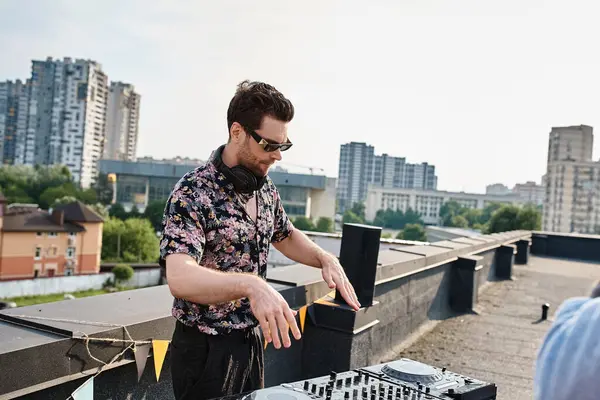 Handsome young male DJ with stylish sunglasses in urban casual attire playing music at rooftop party — Stock Photo