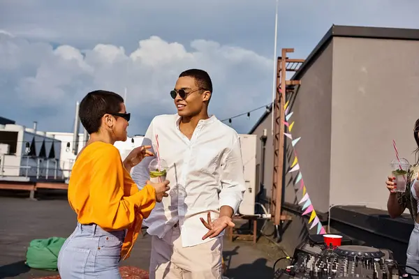 Cheerful woman and african american man in urban clothes with sunglasses partying on rooftop — Stock Photo