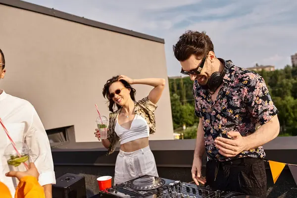Fröhliche schöne Frau in lebendiger Kleidung mit Cocktail in der Hand feiert neben DJ auf dem Dach — Stockfoto