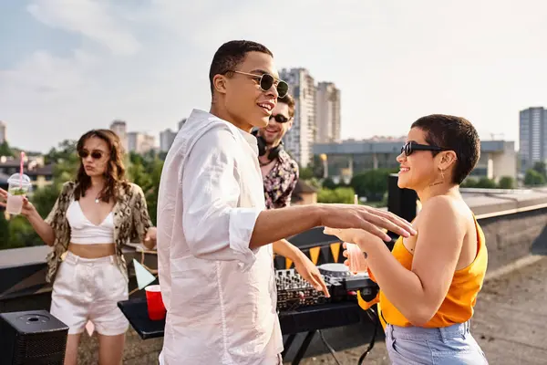 Amigos multiculturais de boa aparência com óculos de sol bebendo e se divertindo na festa no telhado com DJ — Fotografia de Stock