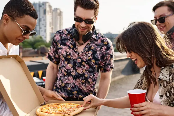 Alegres amigos multirraciales con gafas de sol elegantes que comparten pizza y se divierten en la fiesta en la azotea - foto de stock