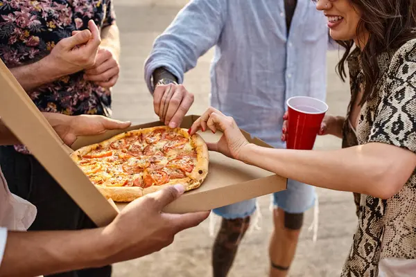 Обрезанный вид мультикультурных друзей в случайных ярких одеждах делятся вкусной пиццей на вечеринке — стоковое фото