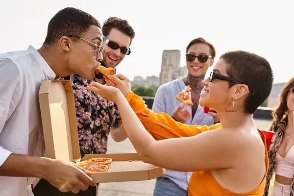 Gente alegre multirracial con gafas de sol de moda comiendo pizza y bebiendo cócteles en la fiesta - foto de stock
