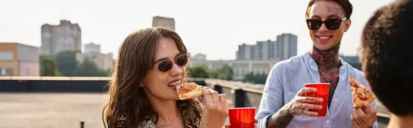 Радісні привабливі друзі в повсякденних яскравих вбраннях їдять піцу і насолоджуються напоями на вечірці, банер — стокове фото