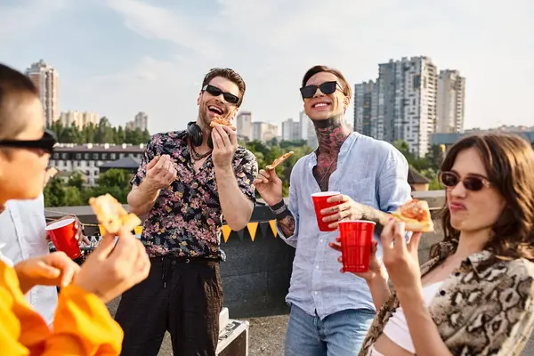 Alegres amigos atractivos con elegantes trajes urbanos comiendo pizza y disfrutando de bebidas en la fiesta - foto de stock
