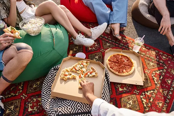 Vista recortada de los jóvenes multirraciales en atuendos casuales disfrutando de pizza y bebidas en la fiesta - foto de stock
