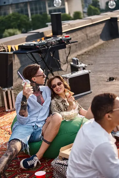 Joyous friends with sunglasses in vivid attires eating pizza and drinking cocktail at party — Stock Photo