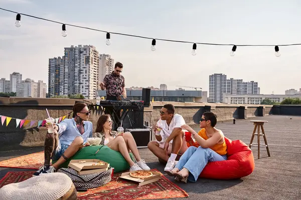Joyful interracial friends in casual attires enjoying cocktails at rooftop party with DJ on backdrop — Stock Photo