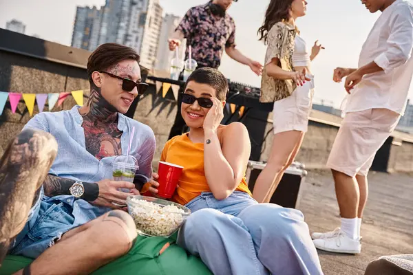 Cheerful multiracial friends enjoying alcohol cocktails at rooftop party with DJ on backdrop — Stock Photo