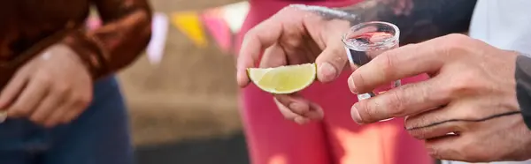 Cropped view of young friends in urban attires preparing to drink tequila with lime and salt, banner — Stock Photo