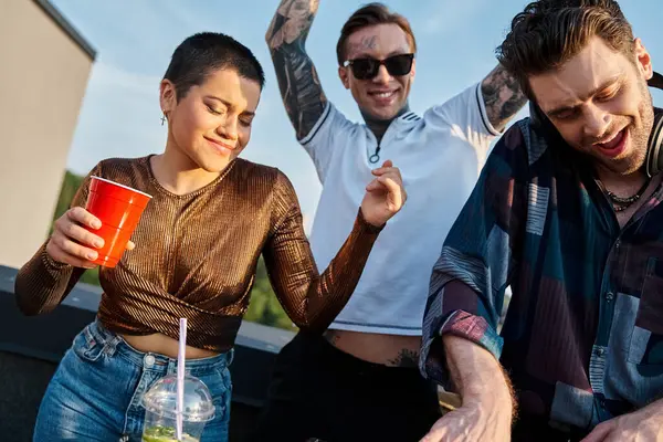 Alegres amigos guapos en atuendos urbanos con gafas de sol de fiesta con su DJ en la fiesta en la azotea - foto de stock