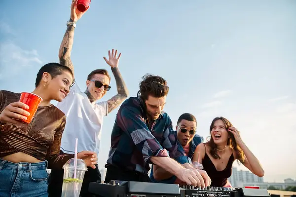 Alegre atractivo diversas personas beber cócteles en la fiesta en la azotea y bailar con apuesto DJ - foto de stock