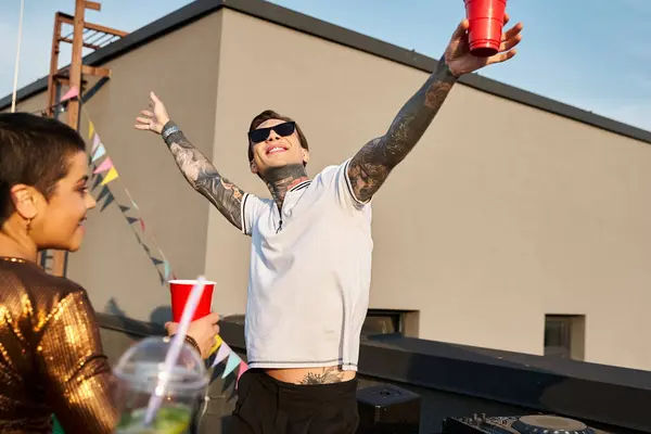 Bel homme joyeux avec des lunettes de soleil et tasse rouge s'amuser avec son bel ami joyeux à la fête — Photo de stock