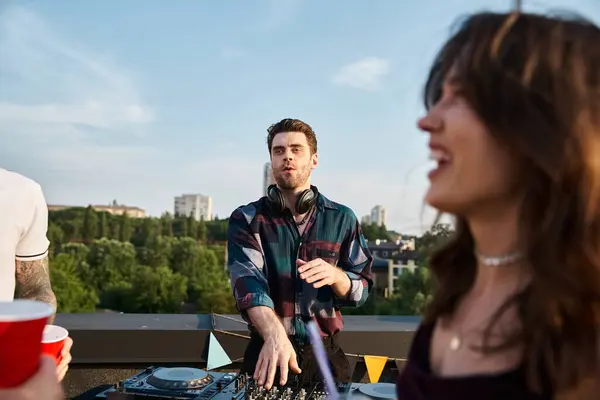 Fokus auf gutaussehenden fröhlichen DJ, der Musik für seine verschwommenen fröhlichen Freunde auf Dachterrassen-Party spielt — Stockfoto