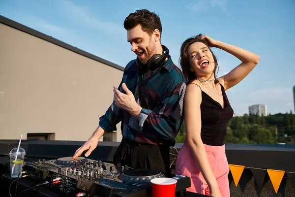 Cheerful attractive woman with long hair having fun at rooftop party next to handsome jolly DJ — Stock Photo