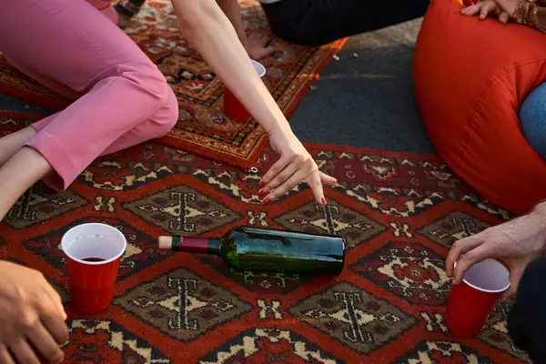 Cropped view of multicultural young people playing spin the bottle while they at rooftop party — Stock Photo