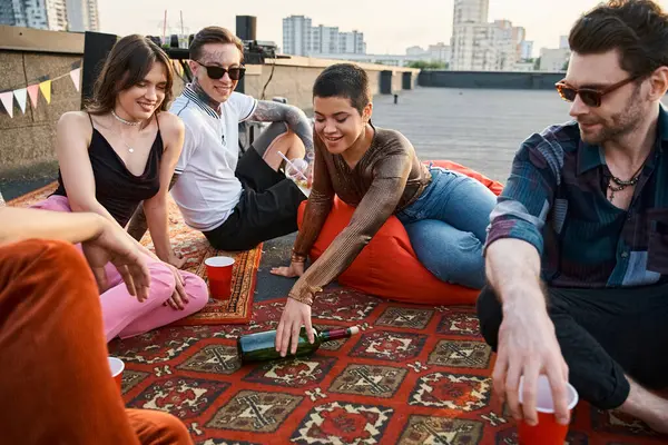 Joyous cheerful diverse friends in casual stylish attires playing spin the bottle together at party — Stock Photo