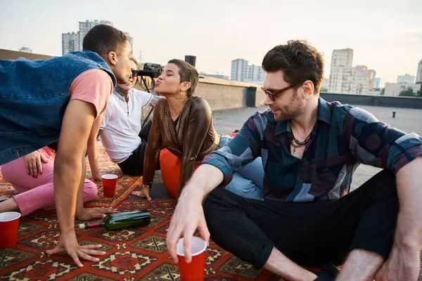 Good looking jolly multiracial friends in urban outfits playing spin the bottle together at party — Stock Photo