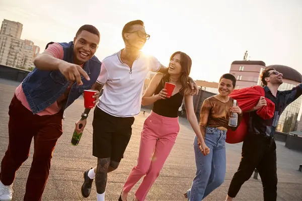 Cheerful multiracial friends with sunglasses with alcohol drinks and bean bag chair at rooftop party — Stock Photo