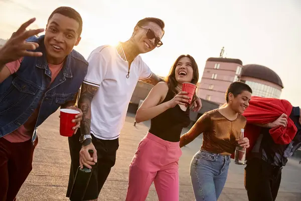 Joyous interracial friends with sunglasses with different drinks and bean bag chair at rooftop party — Stock Photo